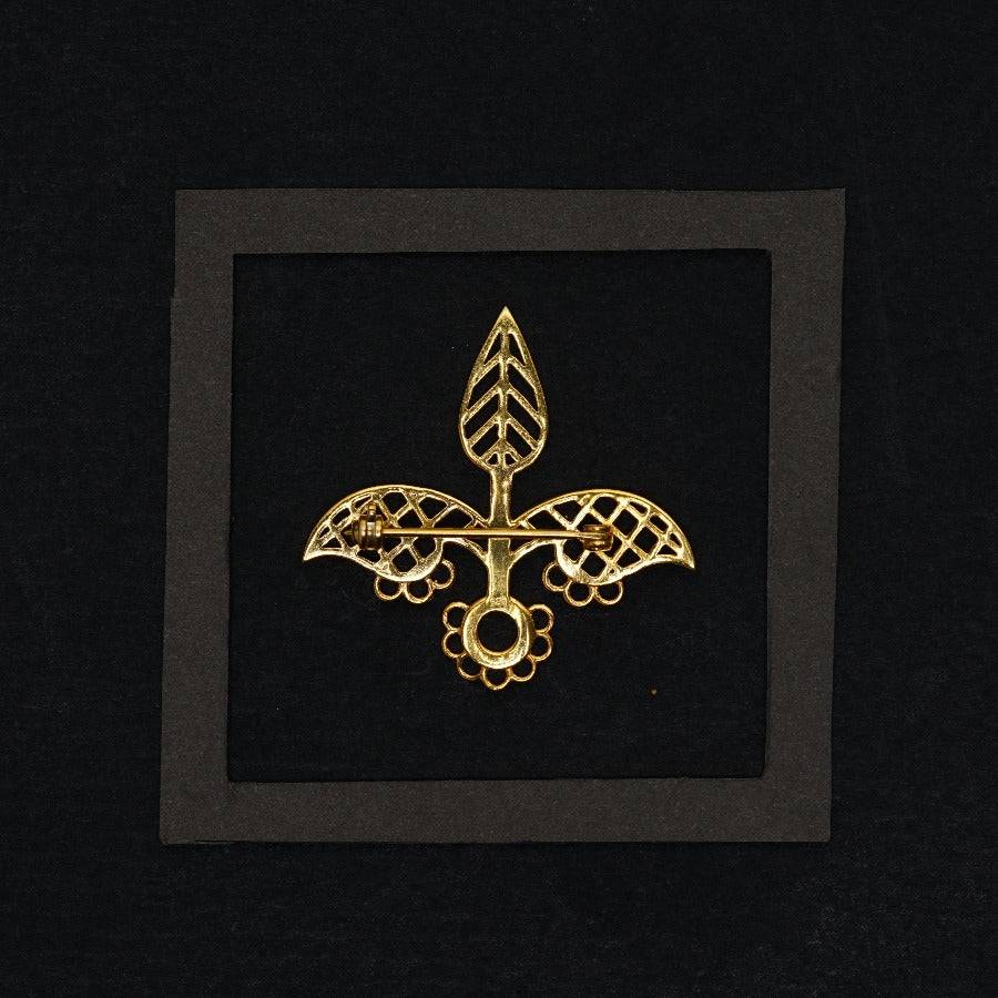 a gold fleur de lis brooch on a black background
