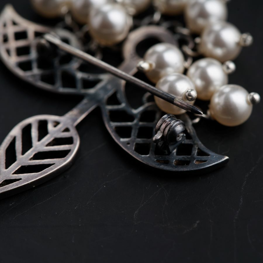 a close up of a brooch with pearls