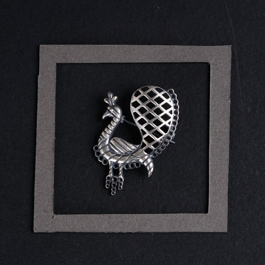 a silver brooch with a bird on it