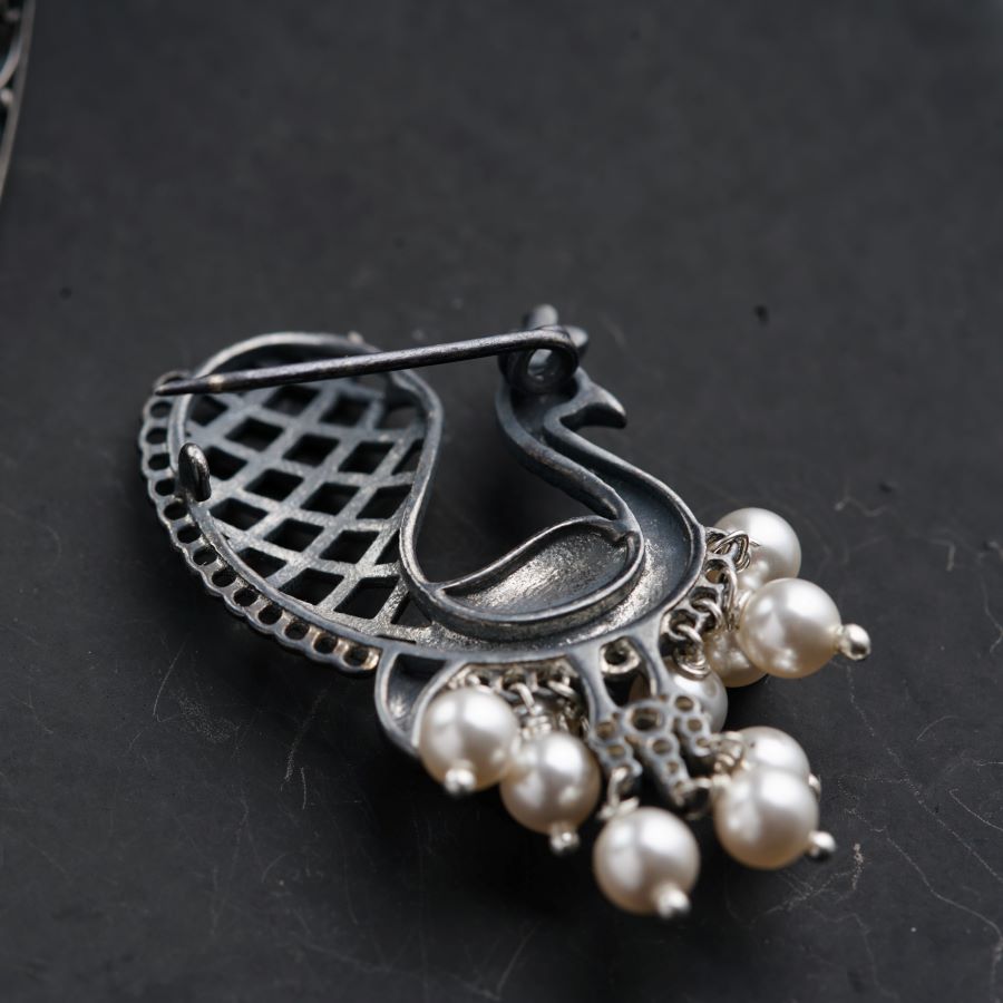 a brooch with pearls on a black surface