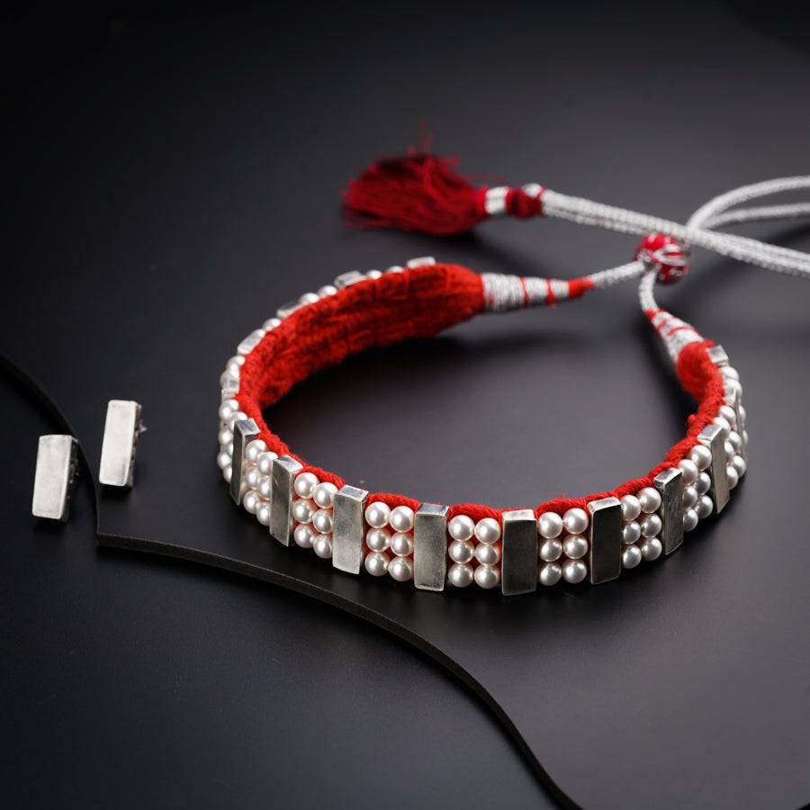 a red string bracelet with silver beads and tassels
