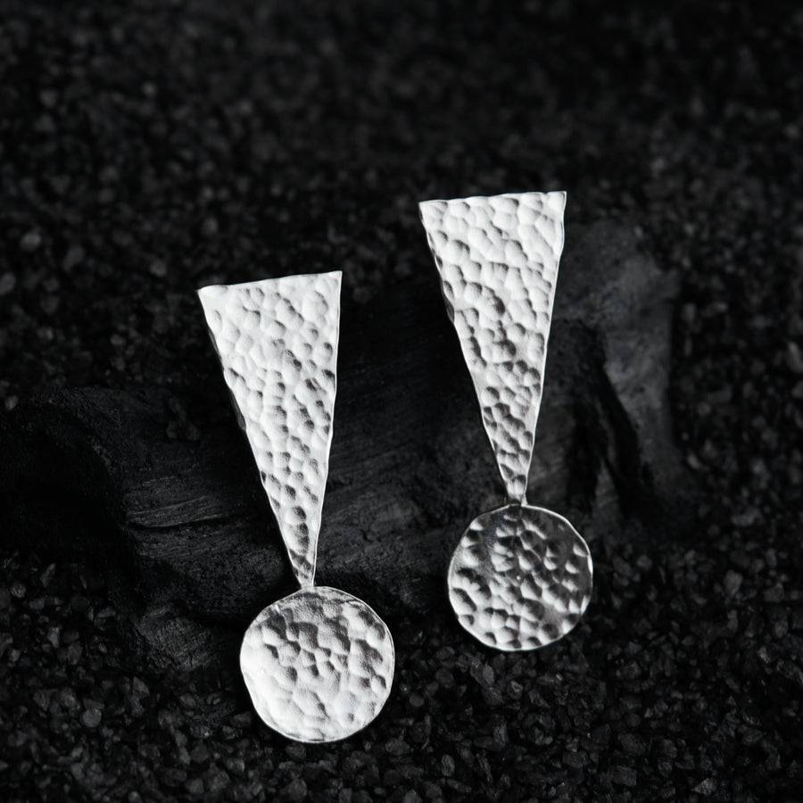 a pair of earrings sitting on top of a rock