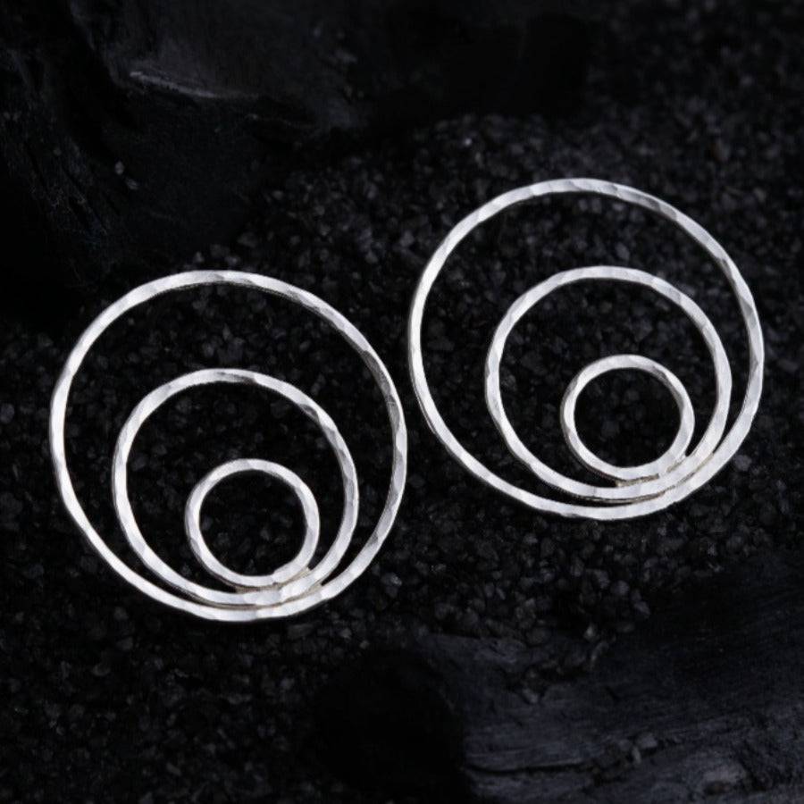 a pair of silver spiral earrings on a black background