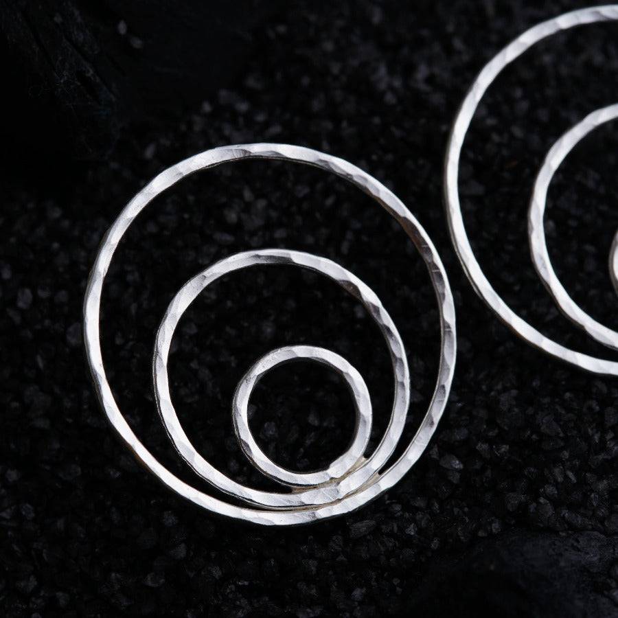 a pair of silver hoop earrings on a black background