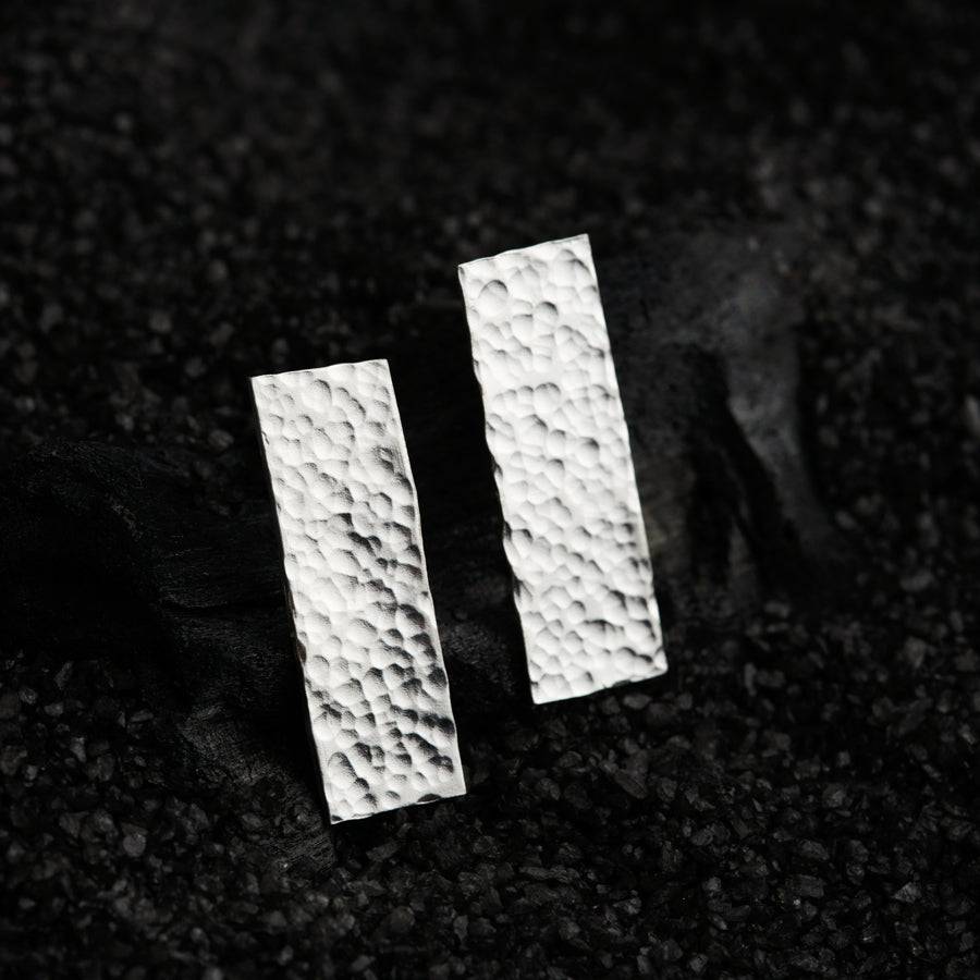 a pair of white square earrings sitting on top of a black surface