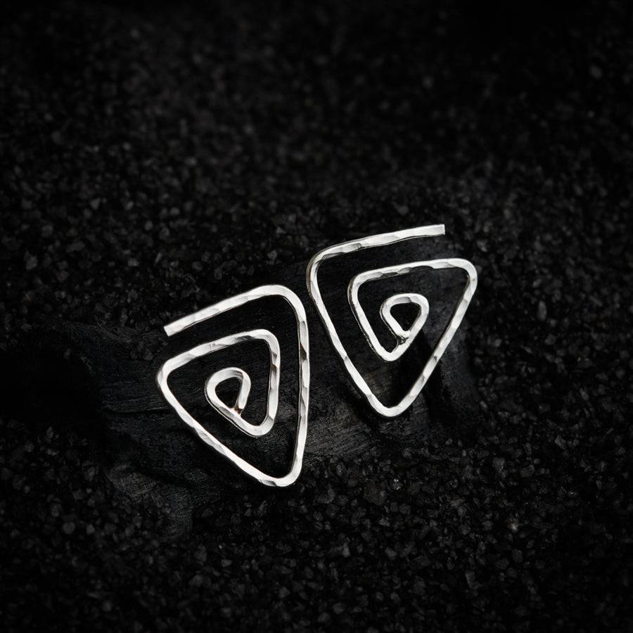 a pair of silver earrings sitting on top of a black surface