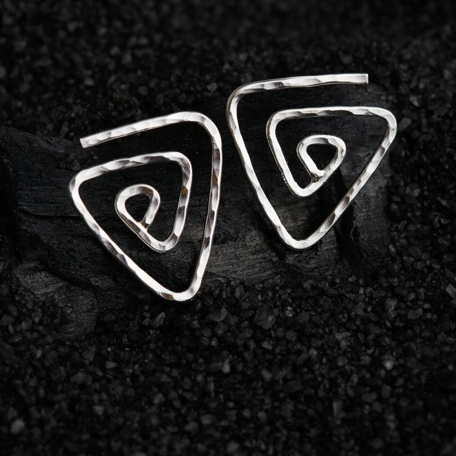 a pair of silver earrings sitting on top of a black surface