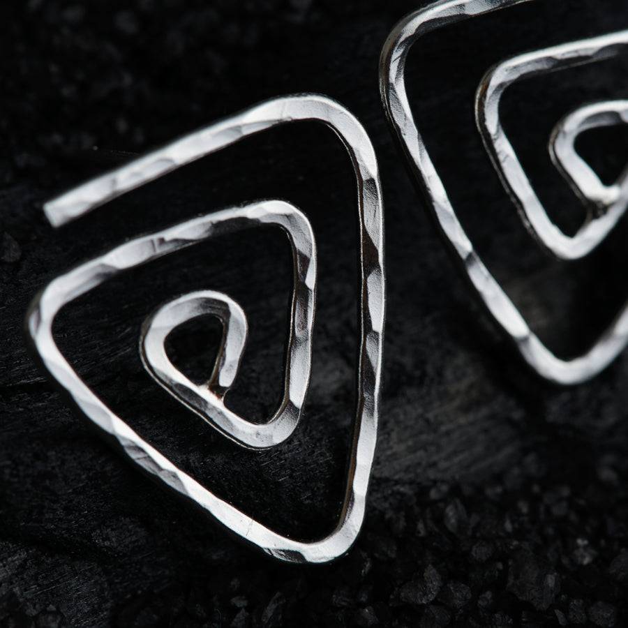 a pair of silver earrings sitting on top of a black surface