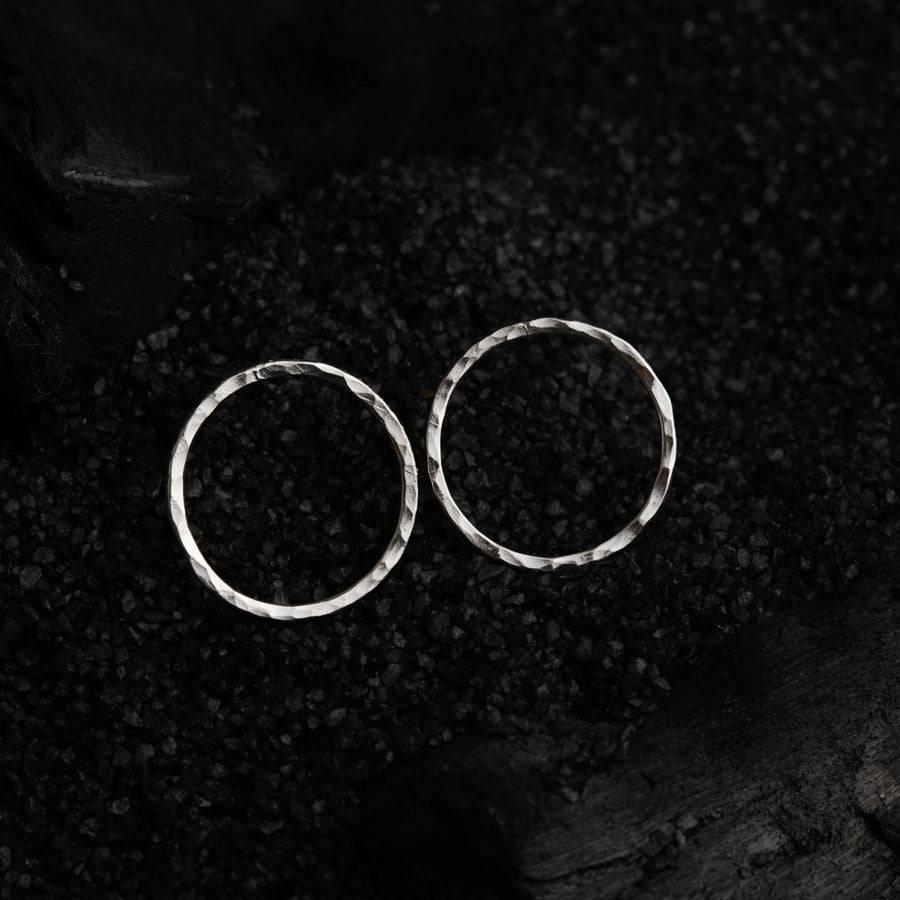 a pair of silver hoop earrings on a black background