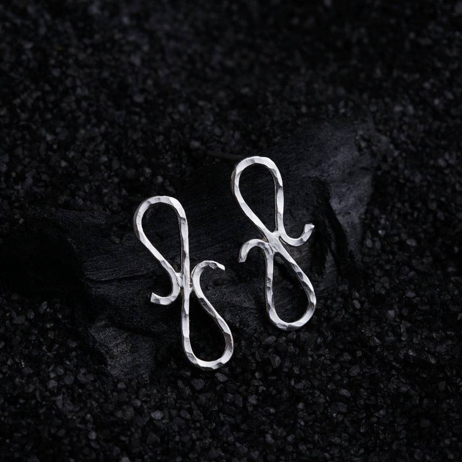 a pair of silver earrings on a black background