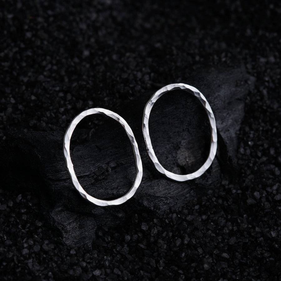 a pair of silver earrings sitting on top of a rock