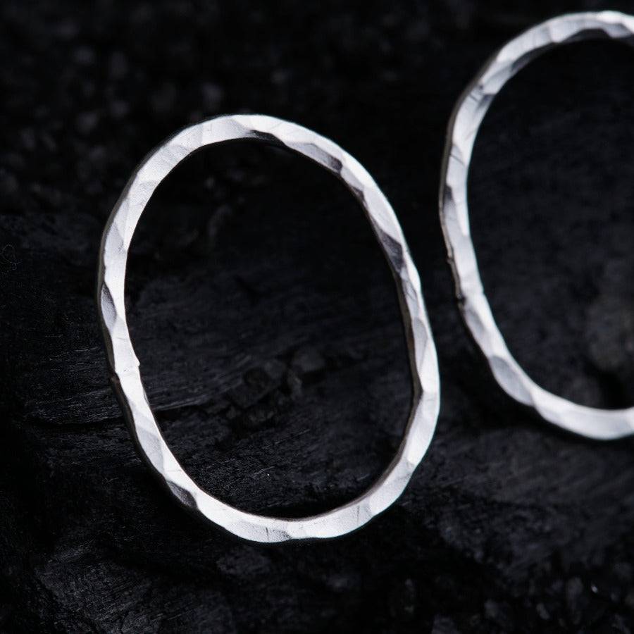 a pair of silver hoop earrings sitting on top of a rock