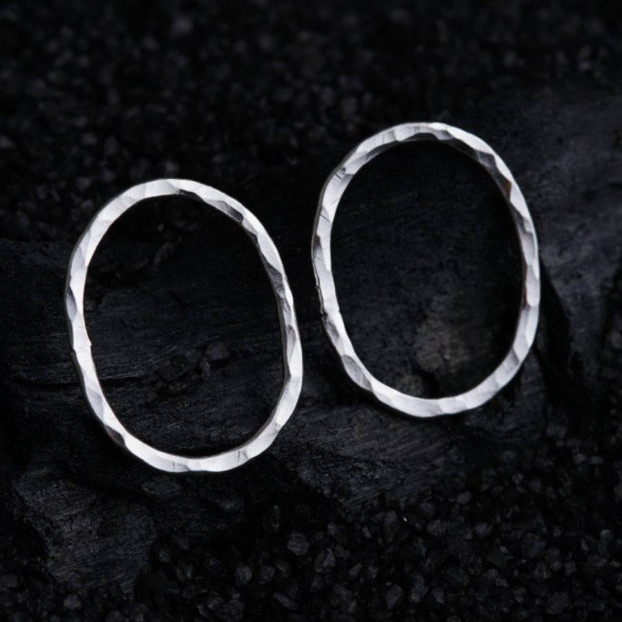 a pair of silver earrings sitting on top of a rock