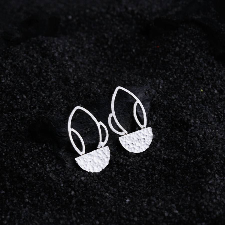 a pair of earrings sitting on top of a black surface