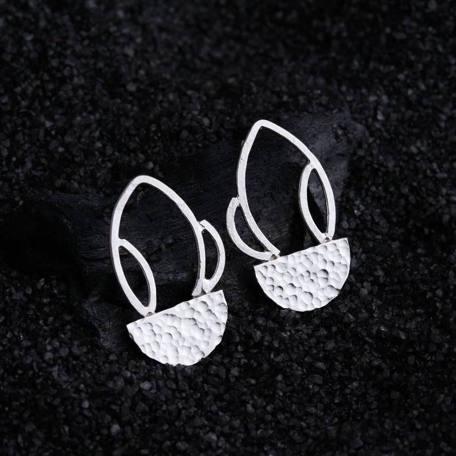 a pair of white earrings sitting on top of a black surface