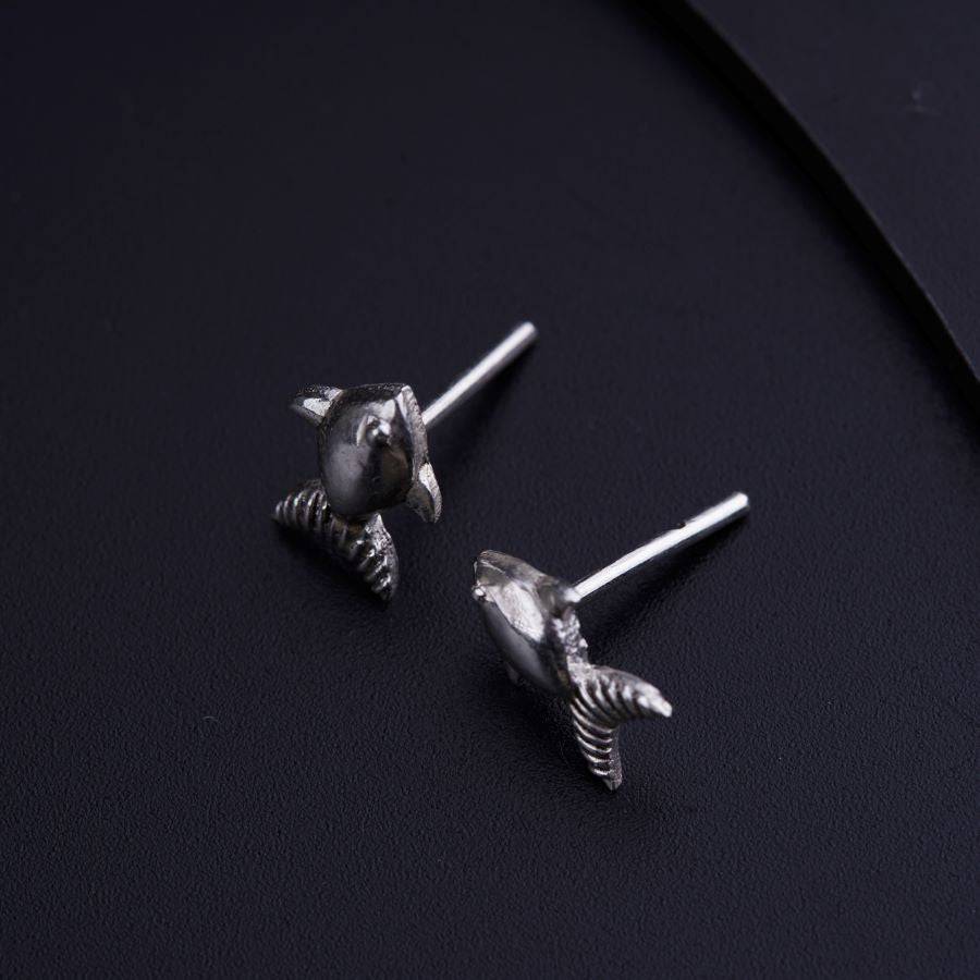 a pair of silver earrings on a black surface