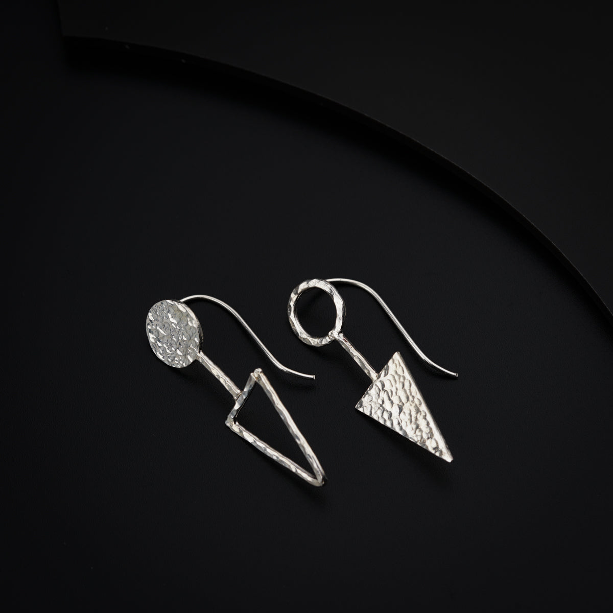 a pair of silver earrings on a black surface