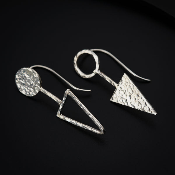 a pair of silver earrings on a black surface