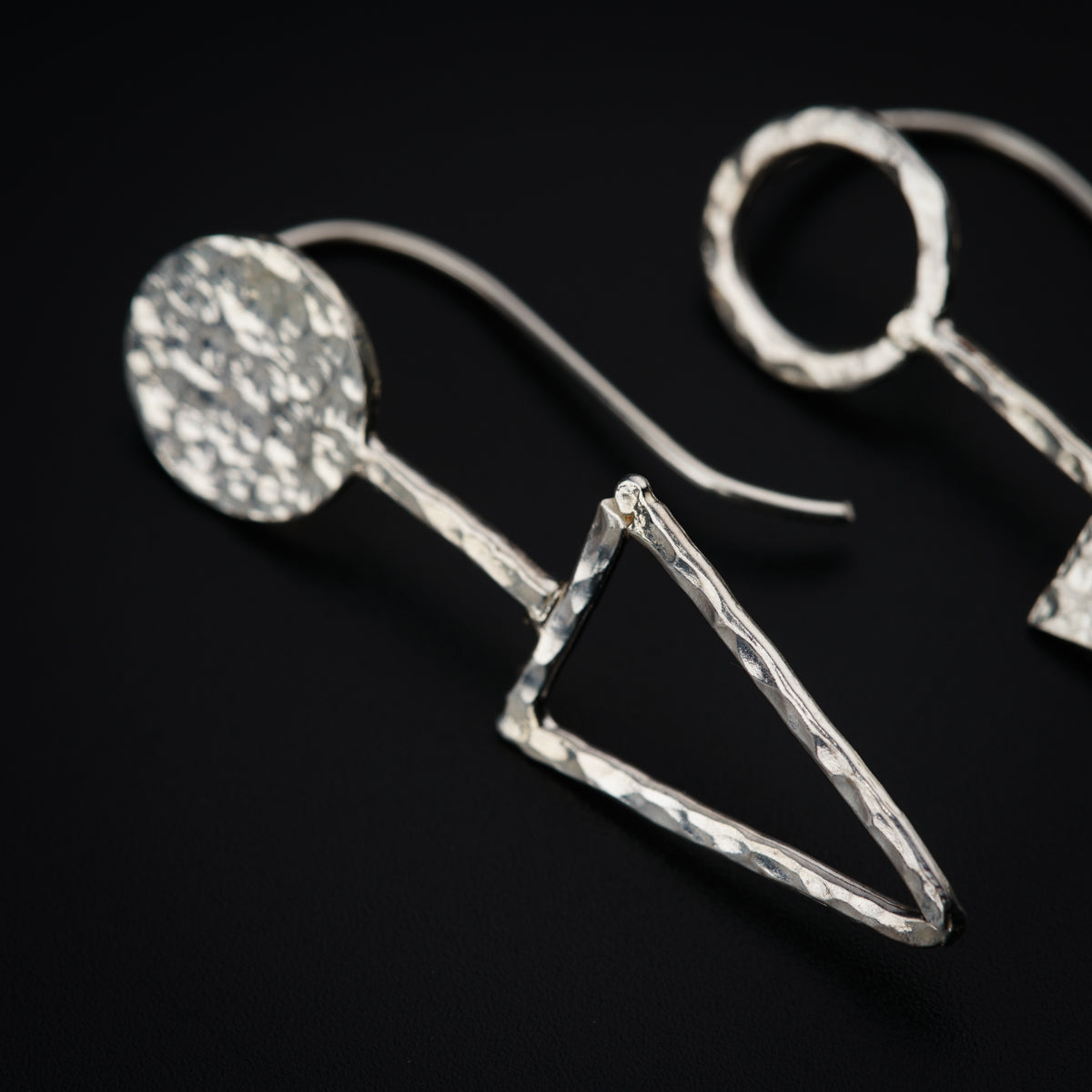 a pair of silver earrings on a black surface