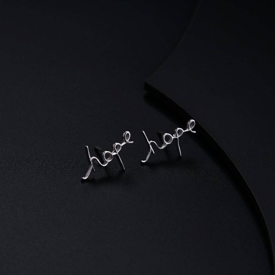 a pair of silver earrings on a black surface