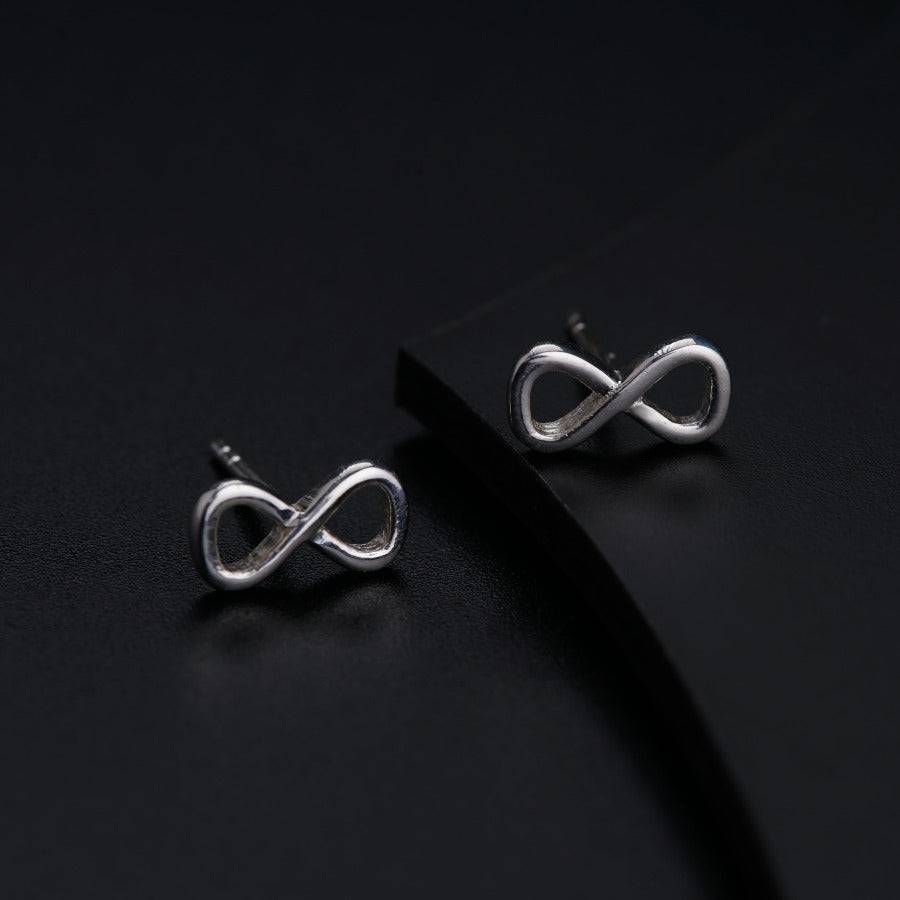 a pair of silver earrings on a black surface