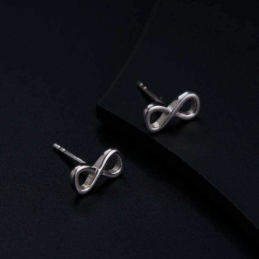 a pair of silver earrings on a black surface