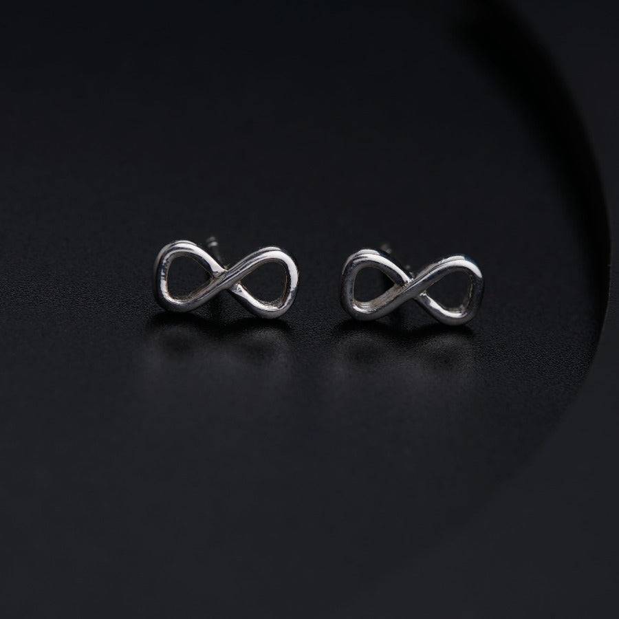 a pair of silver earrings on a black surface