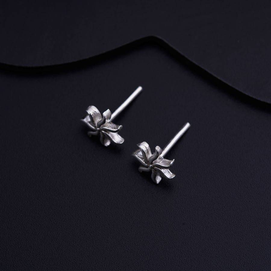a pair of silver flower earrings on a black background