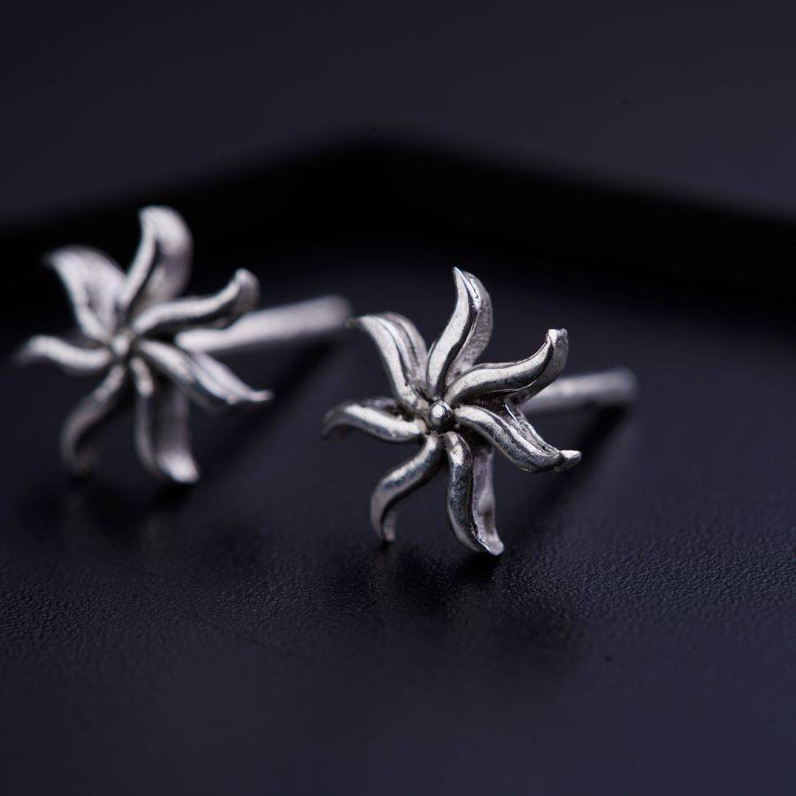 a pair of silver earrings on a black surface