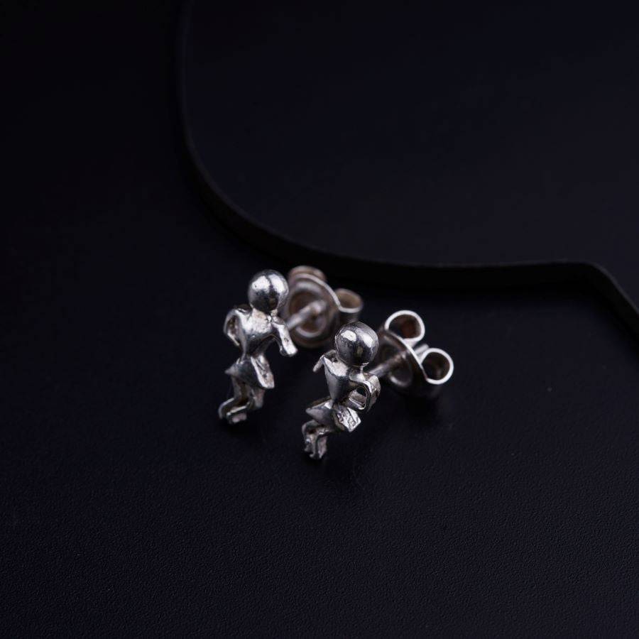 a pair of silver earrings sitting on top of a black surface