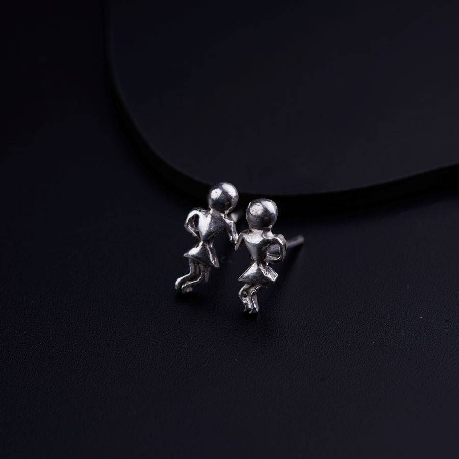 a pair of silver earrings sitting on top of a black surface