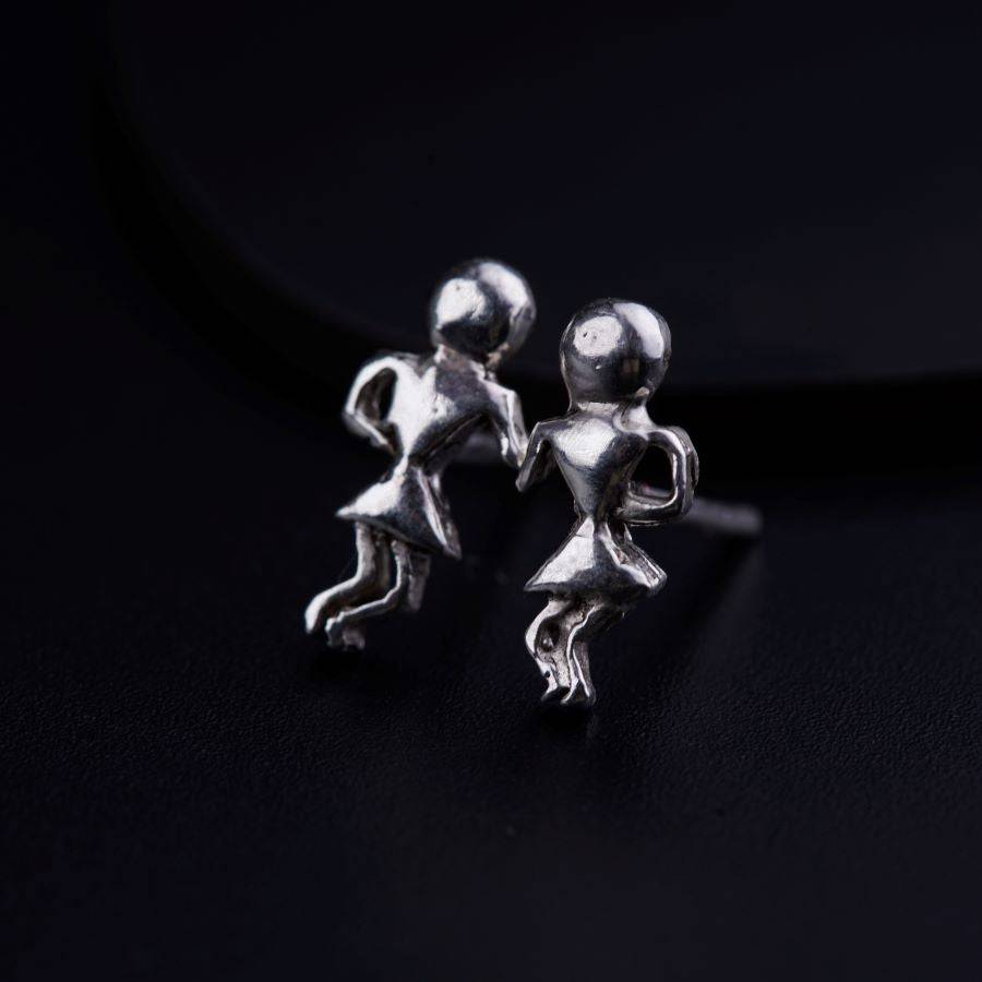 a pair of silver earrings on a black surface