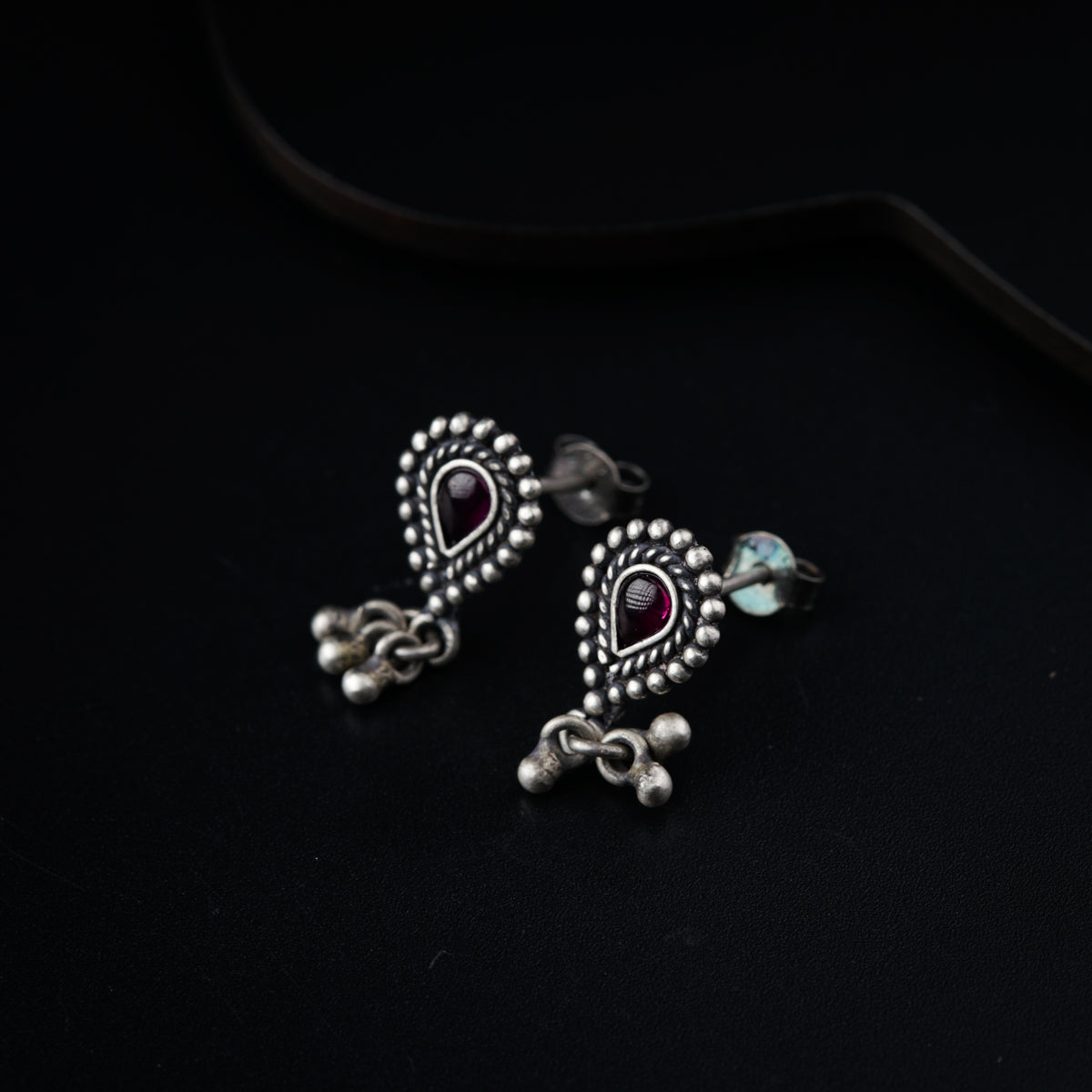 a pair of silver colored earrings on a black surface