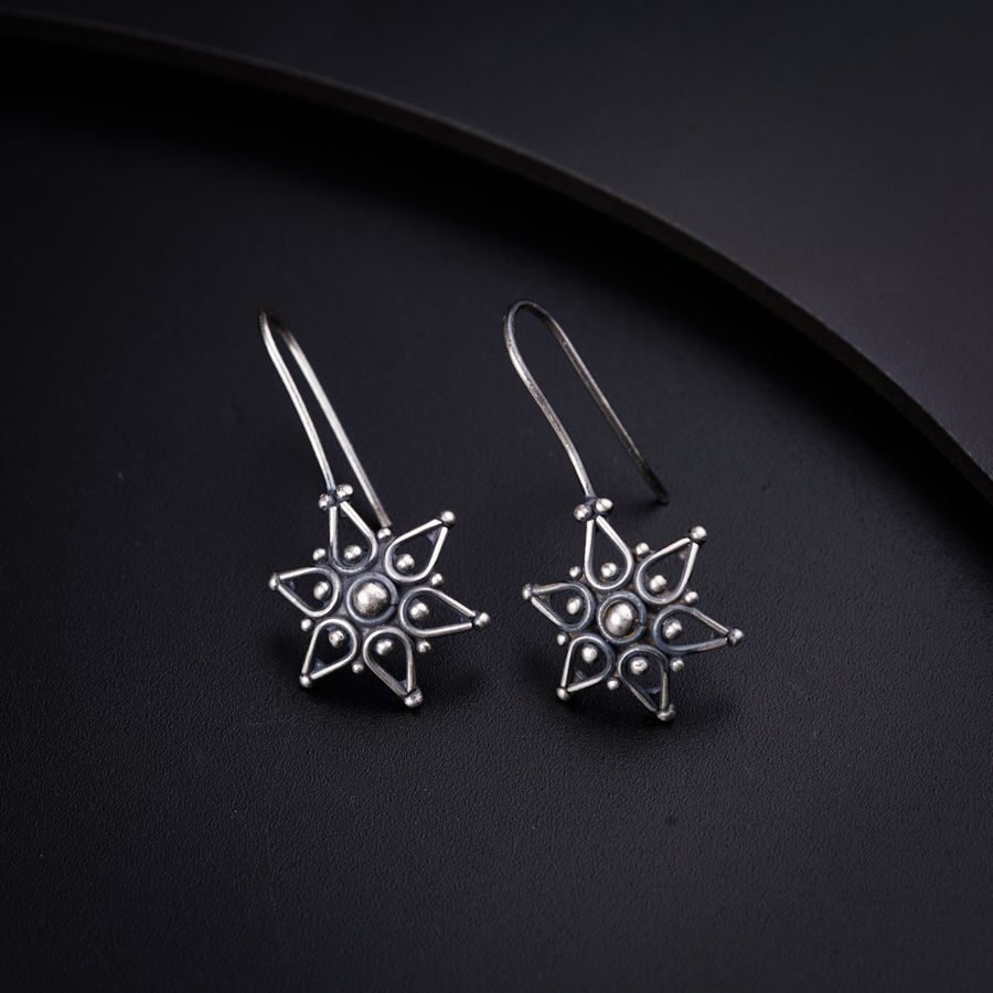 a pair of silver earrings on a black surface