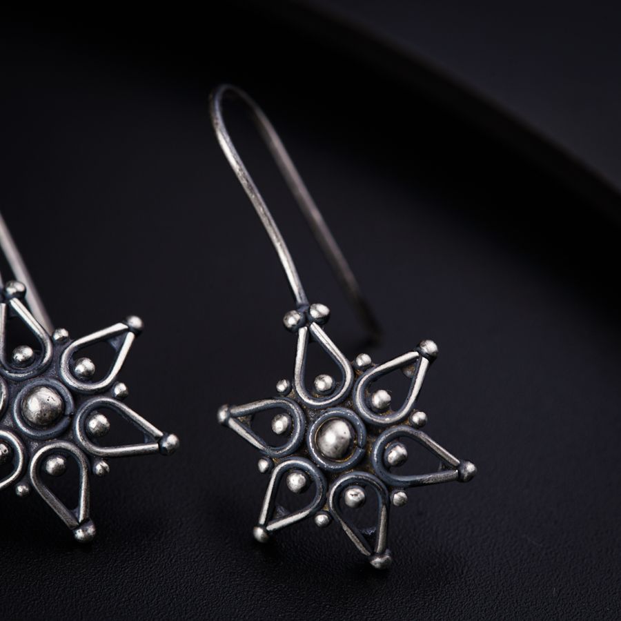 a pair of silver earrings on a black surface
