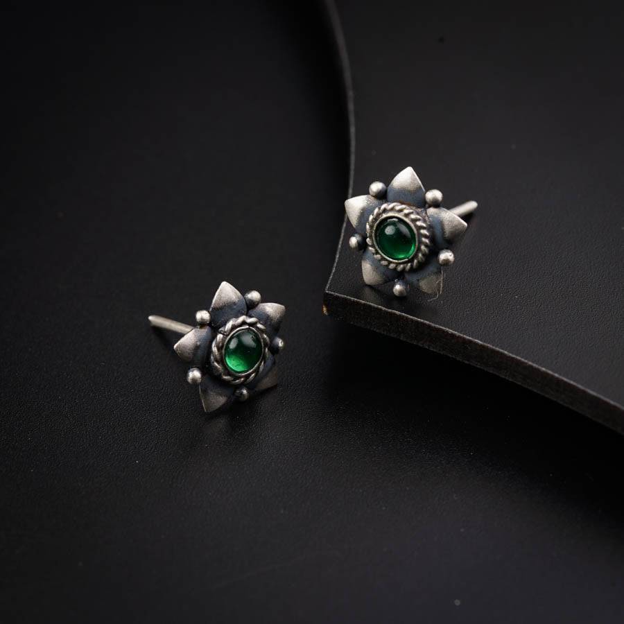 a pair of earrings with a green stone