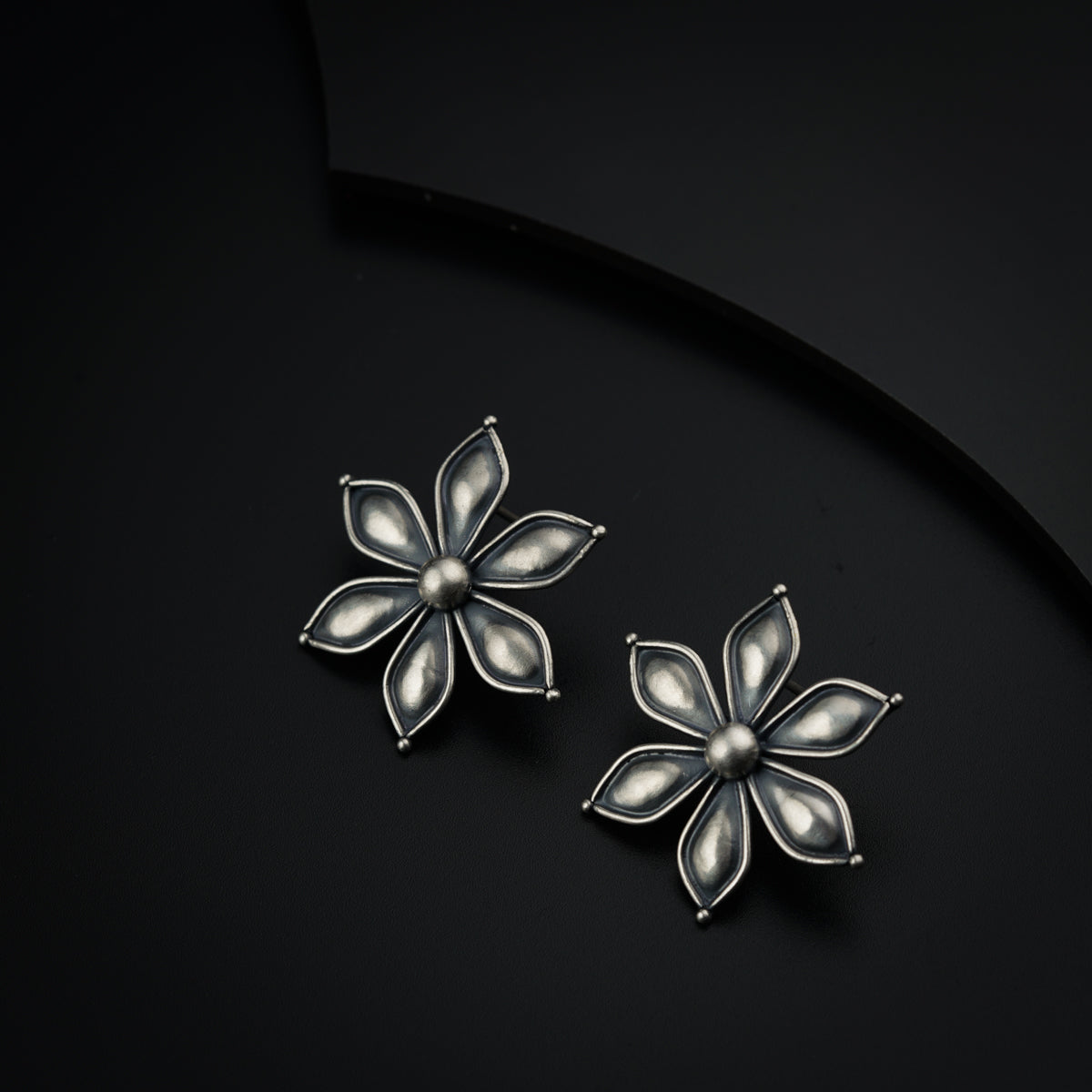 a pair of flower shaped earrings on a black surface