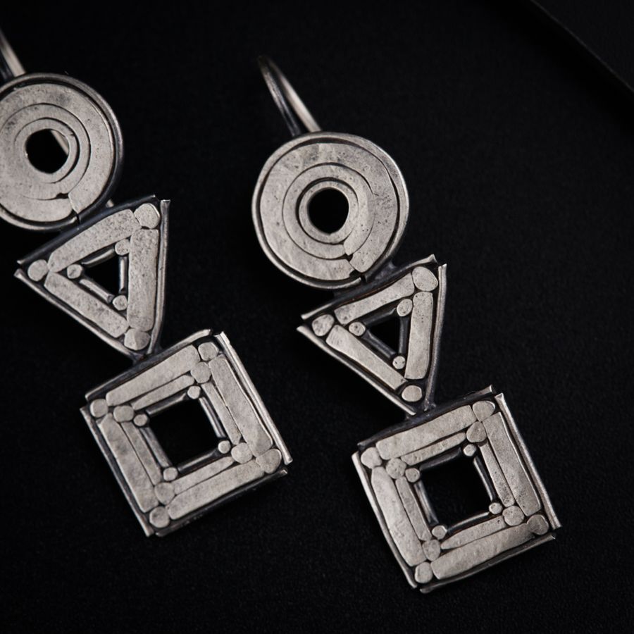 a pair of silver earrings sitting on top of a table