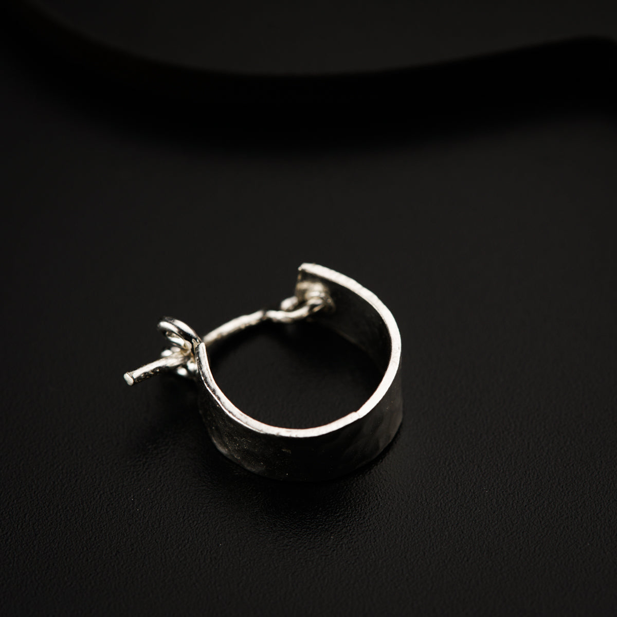a close up of a silver ring on a black surface