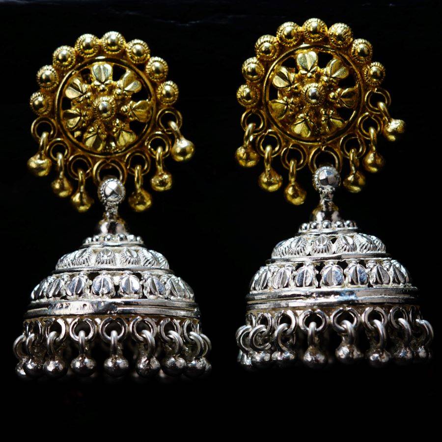 a pair of silver and gold earrings on a black background