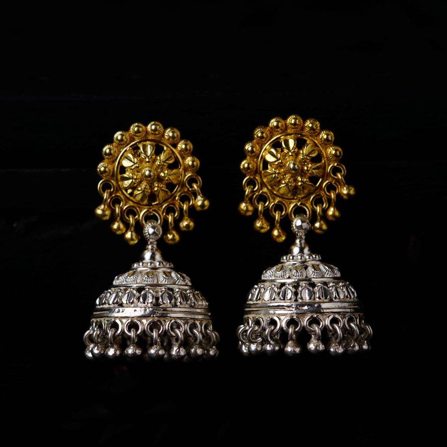 a pair of gold and silver earrings on a black background