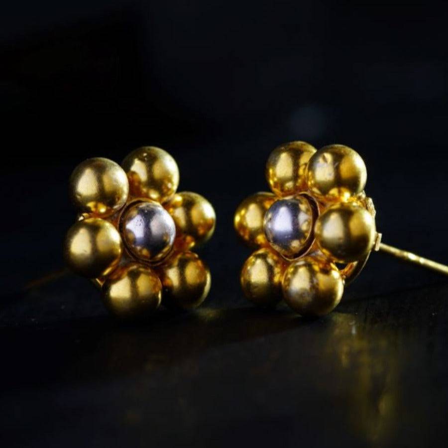 a pair of gold earrings on a black surface