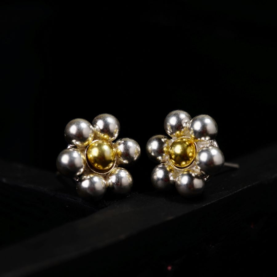 a pair of silver and gold earrings on a black surface