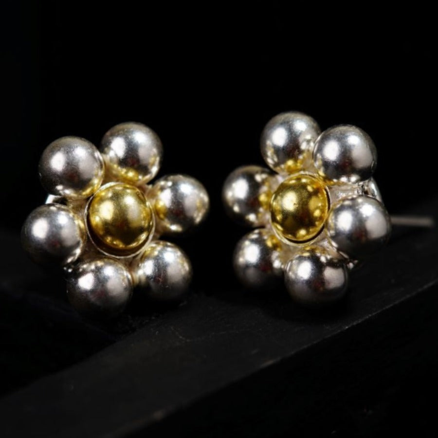 a pair of silver and gold earrings on a black surface