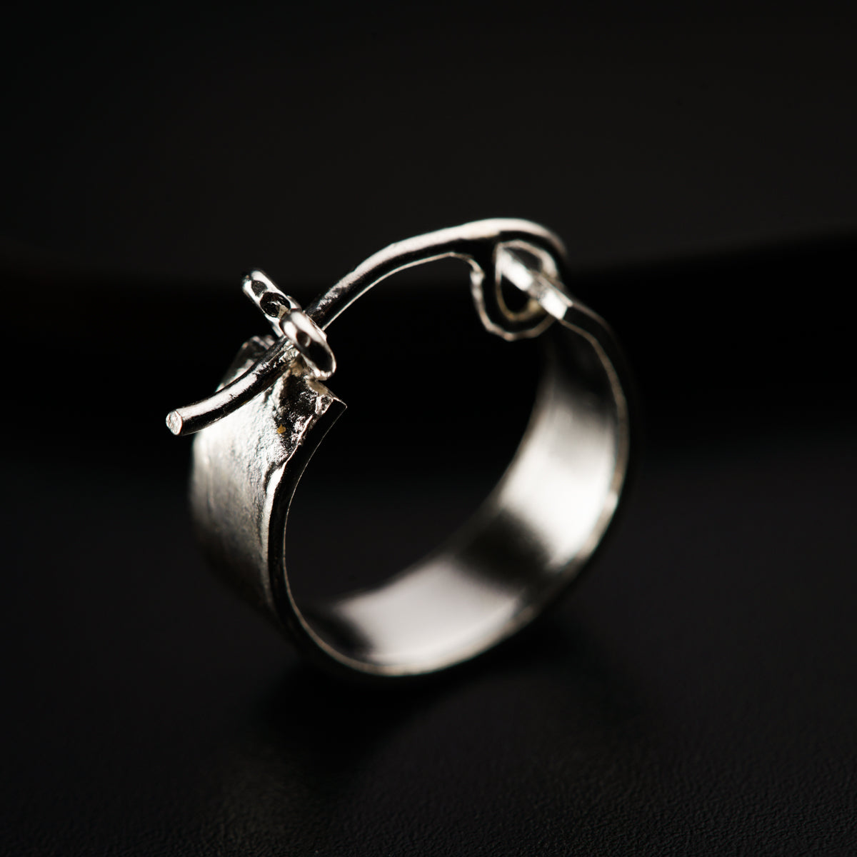 a close up of a silver ring on a black surface