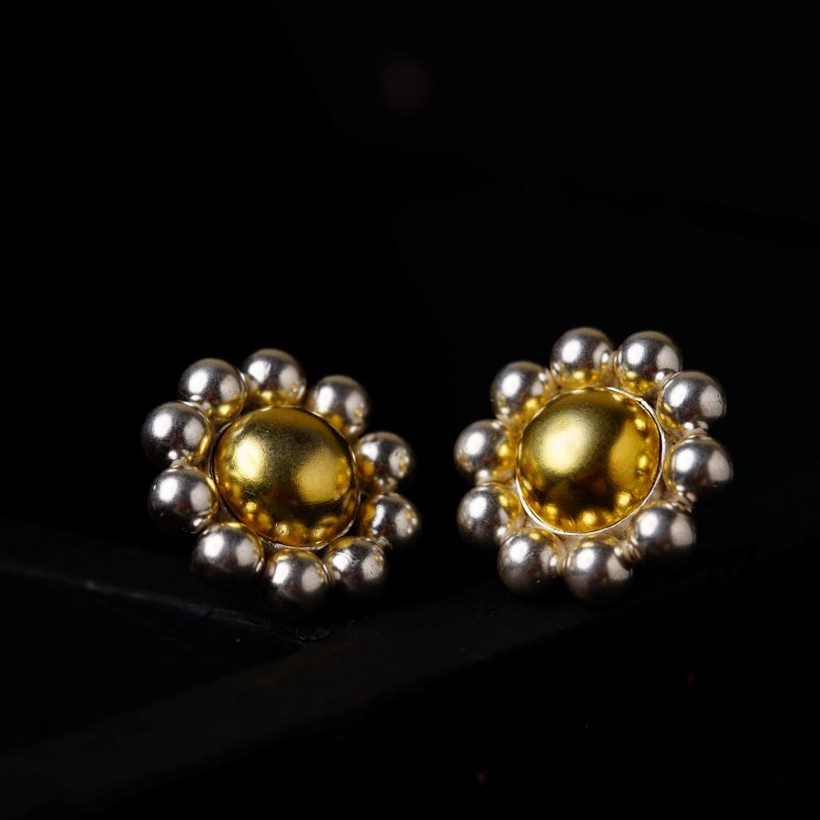 a pair of yellow and silver earrings on a black surface