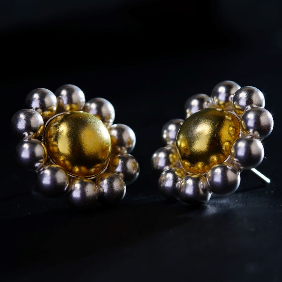 a pair of gold and silver earrings on a black surface