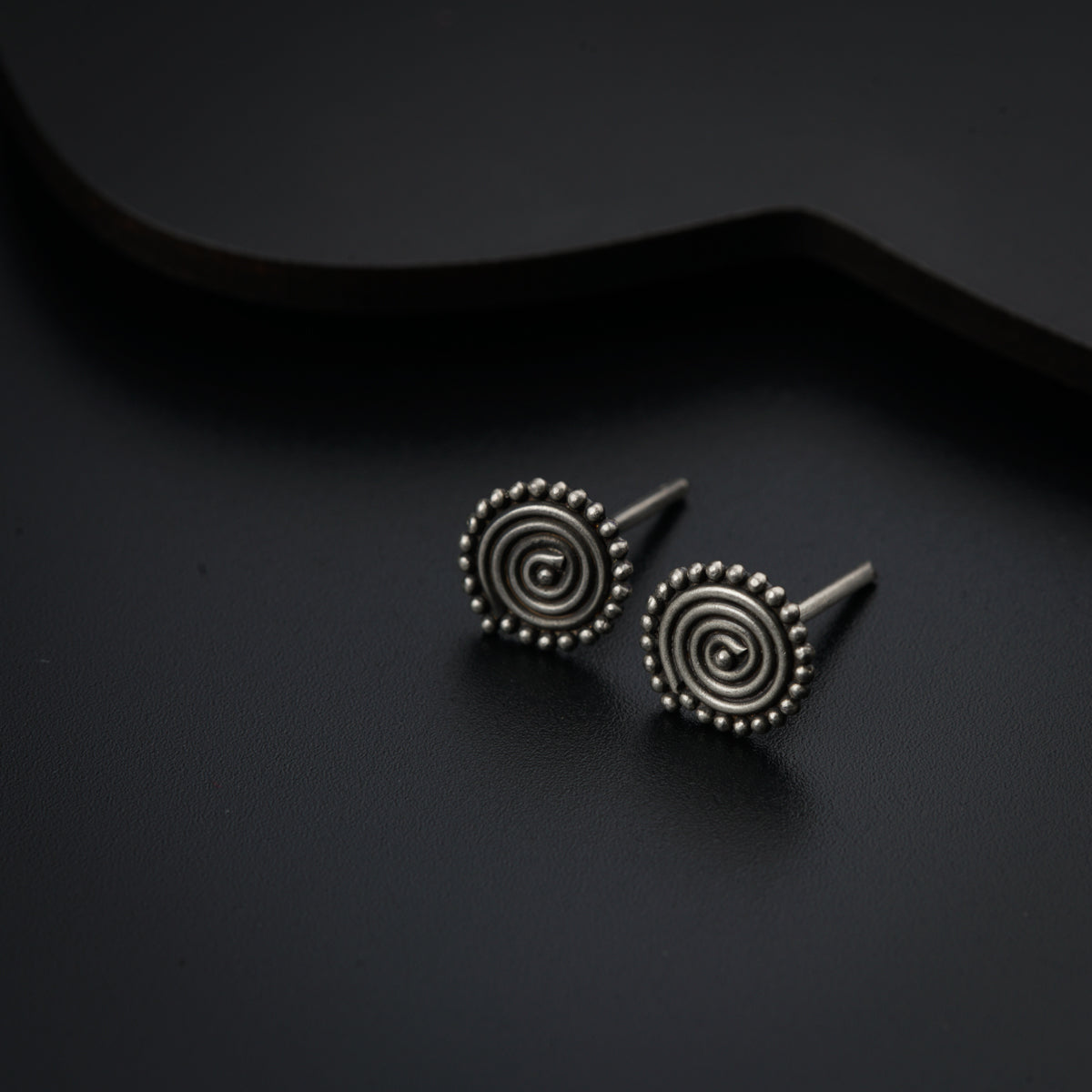 a pair of earrings sitting on top of a black surface