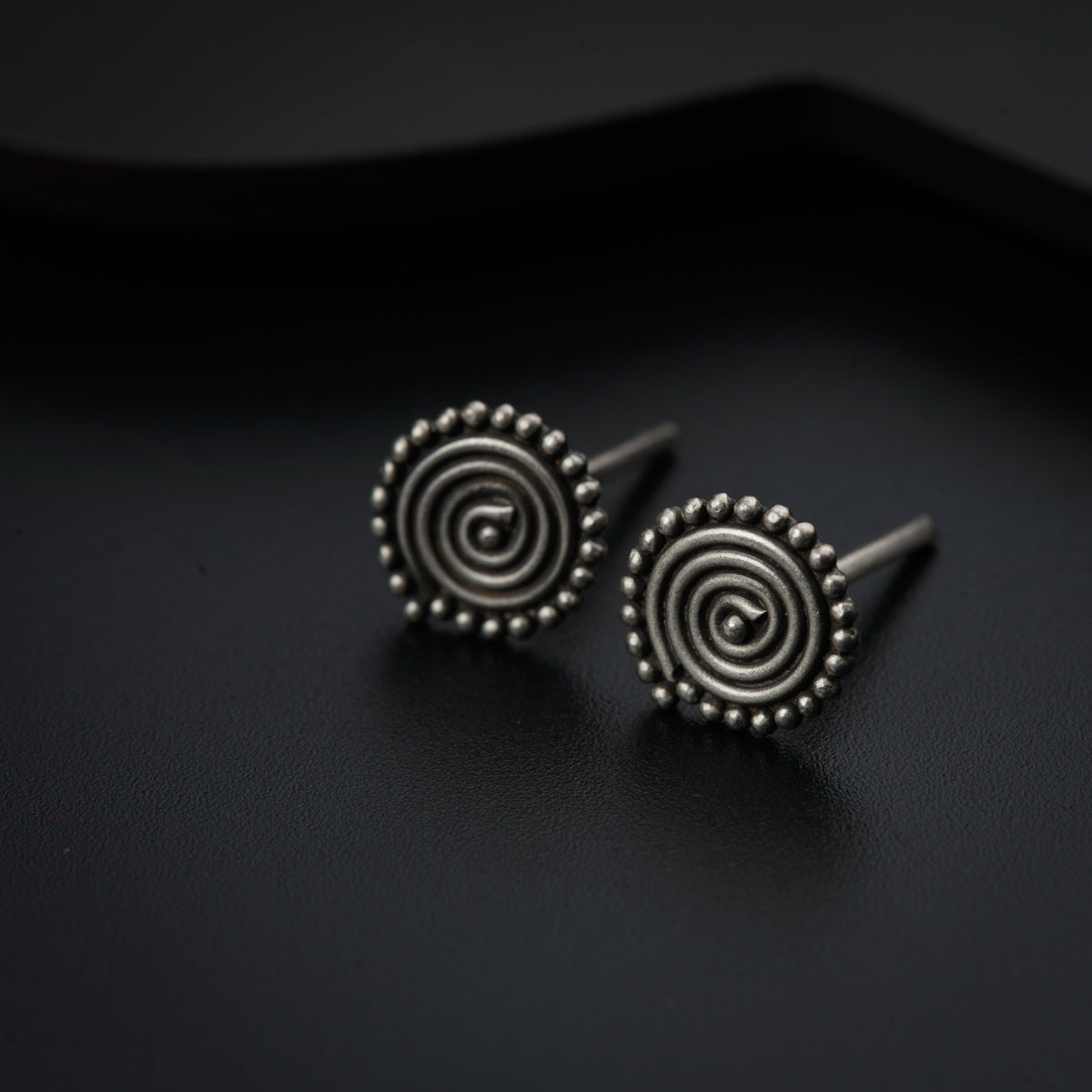a pair of earrings sitting on top of a black surface