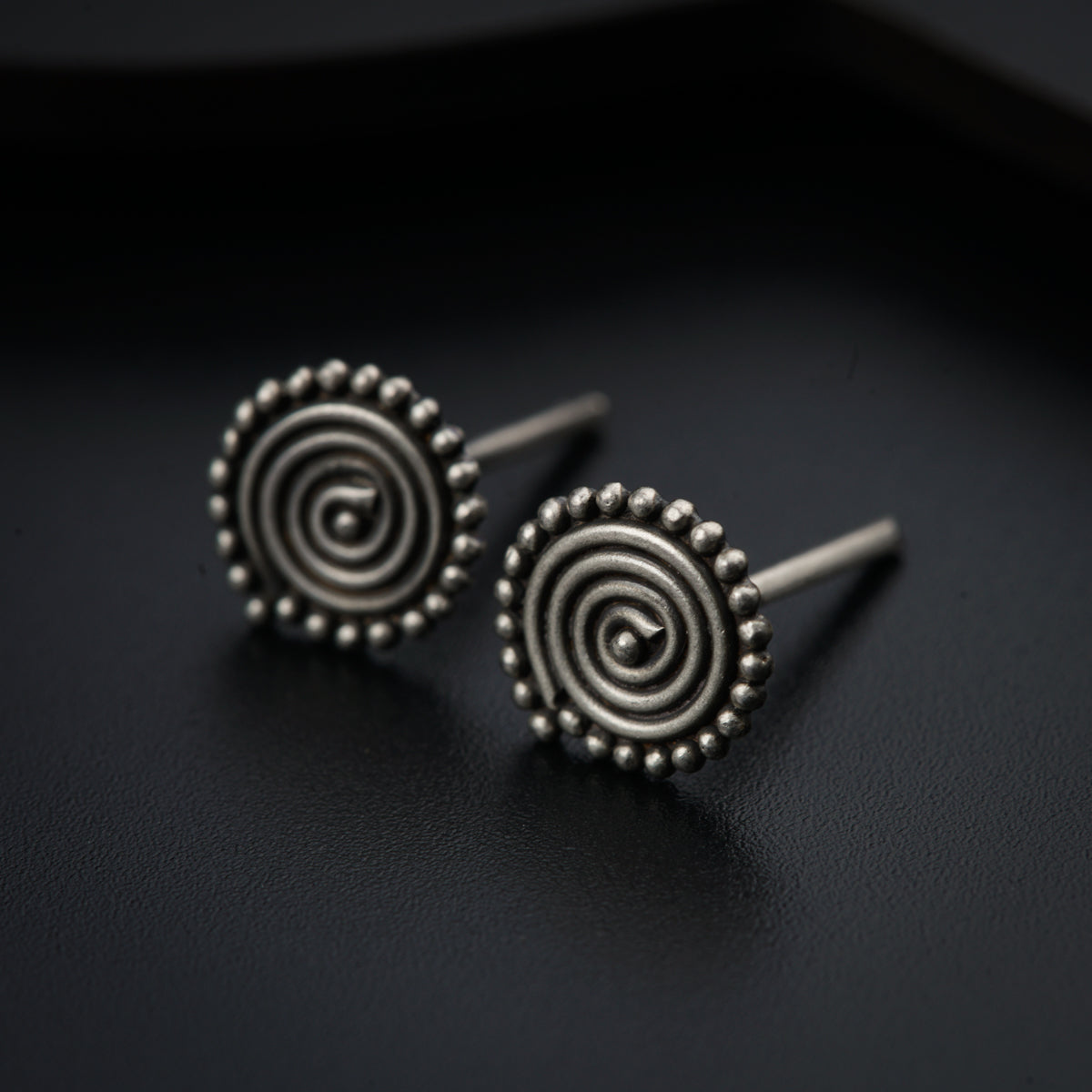 a pair of earrings sitting on top of a black surface